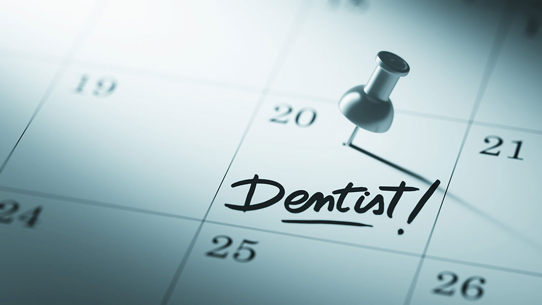 The image features a calendar with the word  Dentist  written on it, indicating an appointment scheduled for dental care.