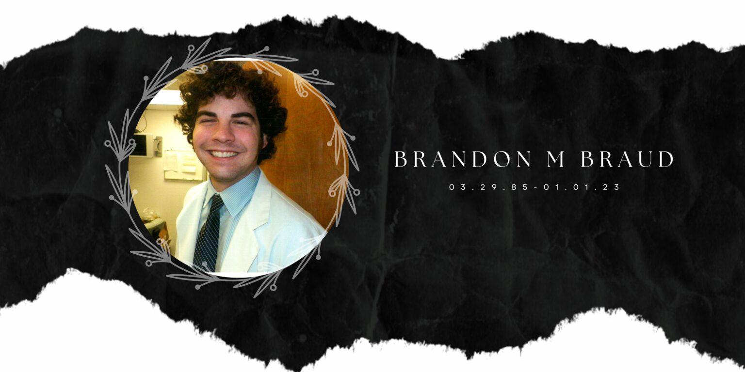 The image shows a person with a beard smiling at the camera, dressed in a white shirt and tie, standing against a black background with a watermark that includes text and a logo.