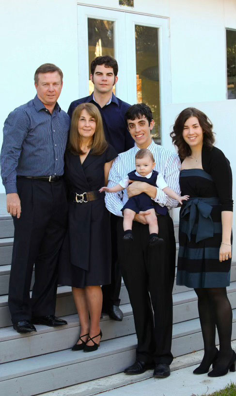 A family posing together on stairs outside a home.