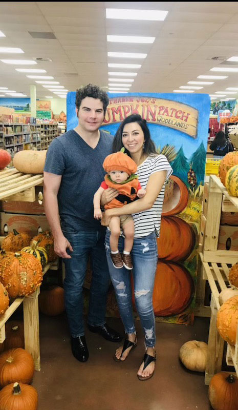 A family posing for a photo at a pumpkin patch.