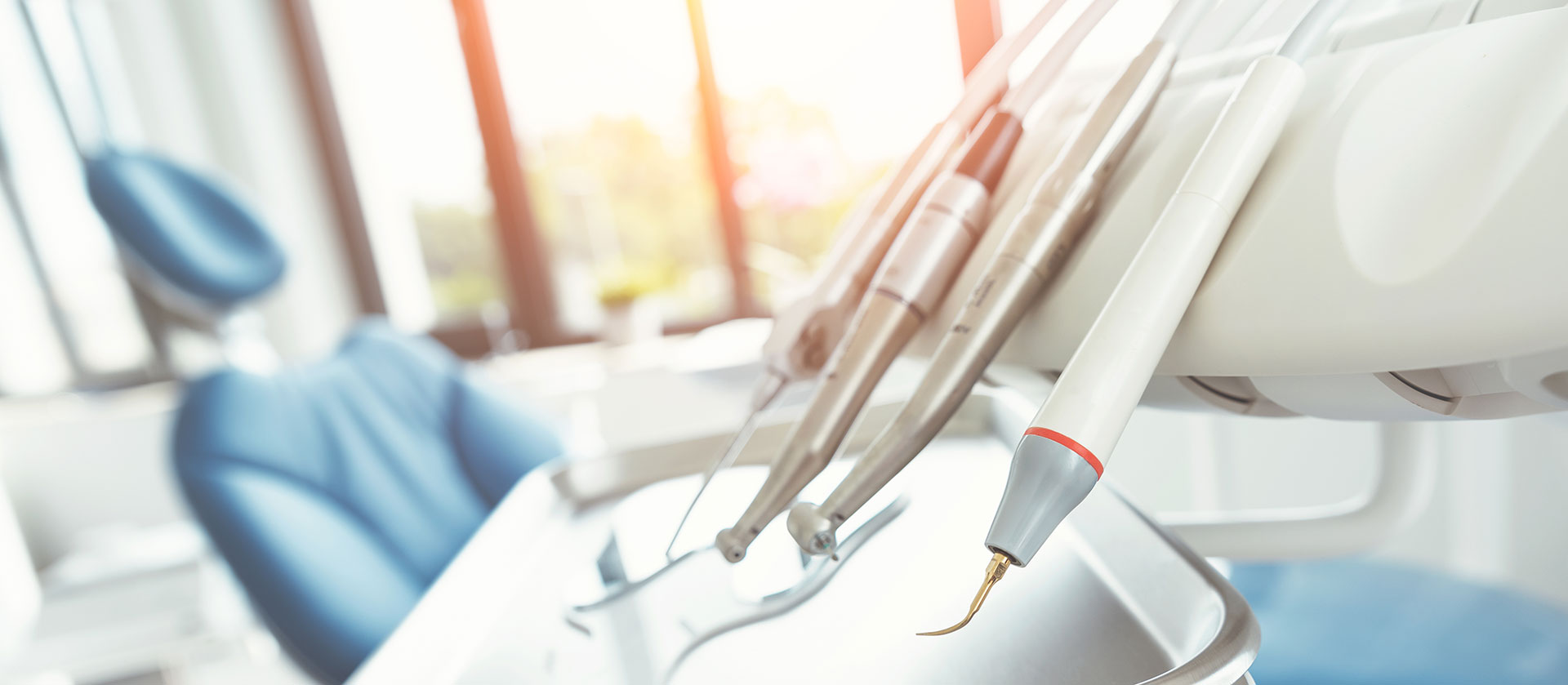 The image shows a blurred interior space with medical equipment, including what appears to be dental tools, suggesting a dental office setting.